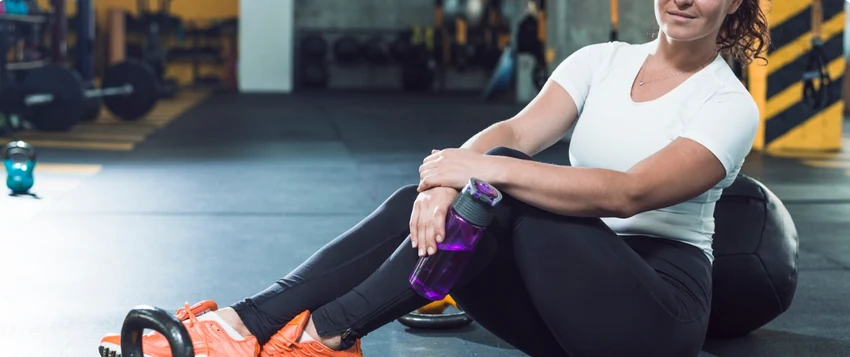 Woman resting with a water bottle after a gym workout