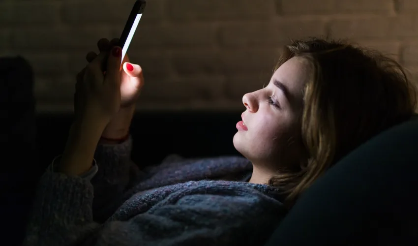 Woman using a smartphone in bed before sleep