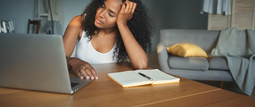 Tired woman experiencing low energy while working on a laptop at home